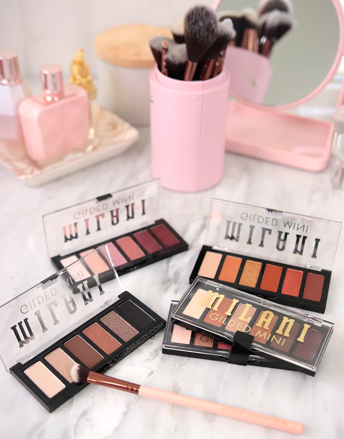milani-gilded-mini-palette-review | Slashed Beauty Five Milani Gilded Mini Eyeshadow Palettes lying on a vanity | Milani Gilded Mini Eyeshadow Palette Review & Swatches | Slashed Beauty