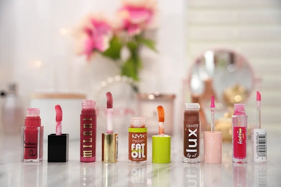 Five drugstore lip oils lined up side by side with their applicators. | The 5 Best Drugstore Lip Oils Tested & Compared | She Beauty